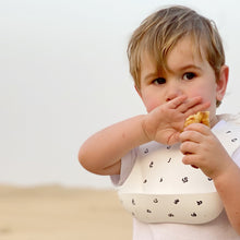 Load image into Gallery viewer, Baby Boss ME bib is made of ultra-soft food grade silicone (0% BPA, PVC and phthalates) and it comes with a comfortable & adjustable neck strap and a large spill pocket. The design features a unique Arabic alphabet pattern. The bib is quick and easy to clean, and the bib packaging is 100% biodegradable. Baby bib, kids bib, toddler bib. Dubai, Abu Dhabi, UAE.
